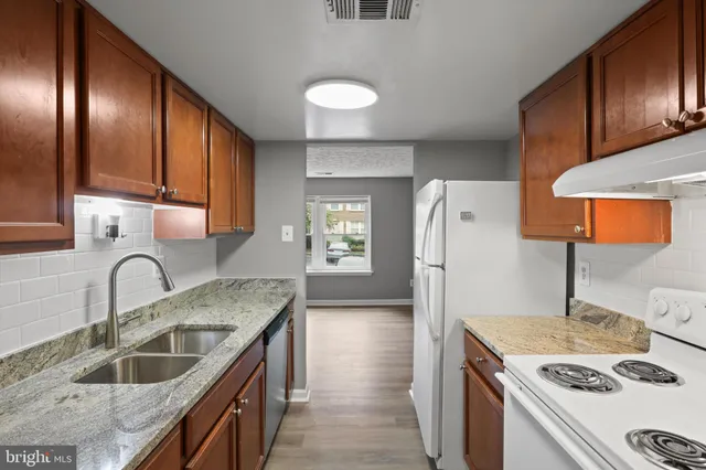 a kitchen with granite countertop a sink stove and refrigerator
