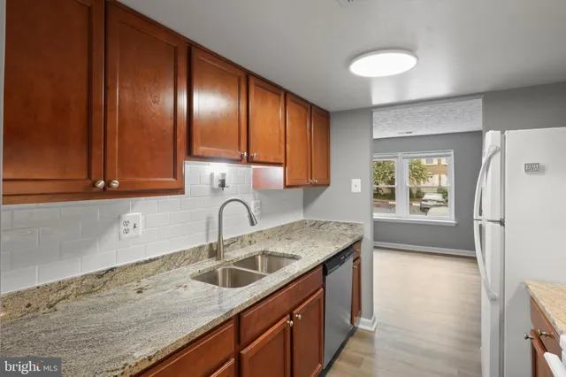 a kitchen with granite countertop stainless steel appliances a sink a refrigerator and cabinets