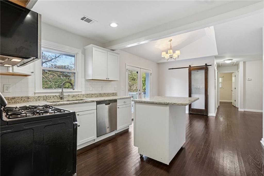 4938 White Boulevard Southwest Mableton, GA 30126 - Photo 5 of 39 a kitchen with granite countertop a stove top oven a sink dishwasher and white cabinets with wooden floor