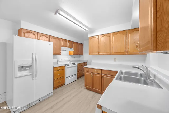 a kitchen with stainless steel appliances granite countertop a refrigerator a sink dishwasher and wooden cabinets with wooden floor