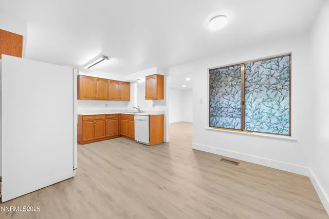 a view of kitchen with stainless steel appliances wooden floor and window
