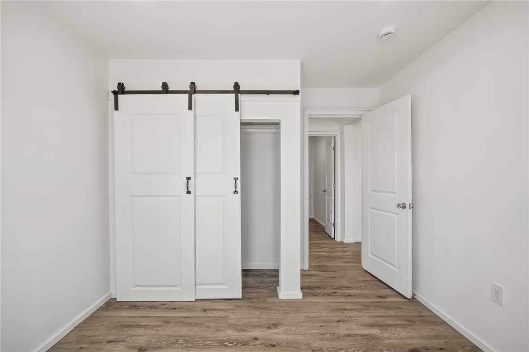 4392 Rio Verde Drive Fort Mohave, AZ 86426 - Photo 12 of 19 Bedroom featuring wood-finish flooring, white walls, and a white barn door closet system with black hardware