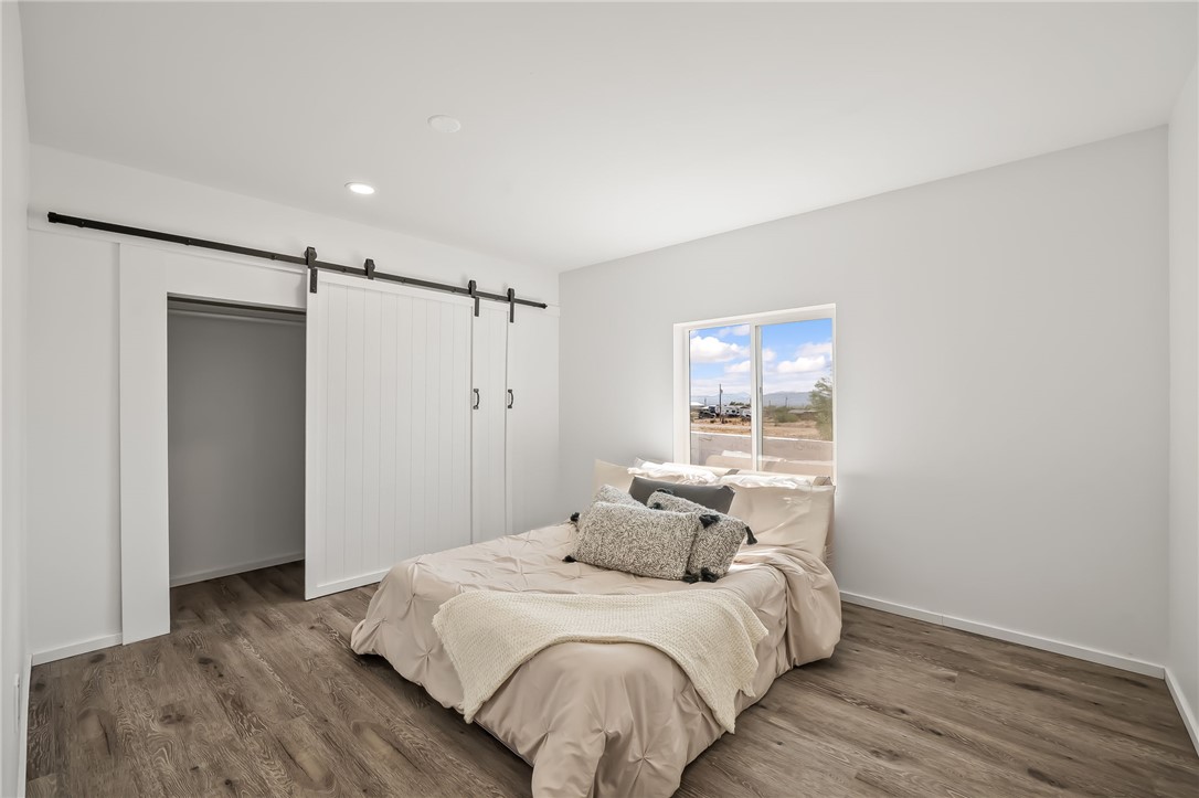 4392 Rio Verde Drive Fort Mohave, AZ 86426 - Photo 13 of 19 Spacious bedroom featuring wood-finish flooring, a contemporary sliding barn door closet system, a large window, recessed lighting, and crisp white walls