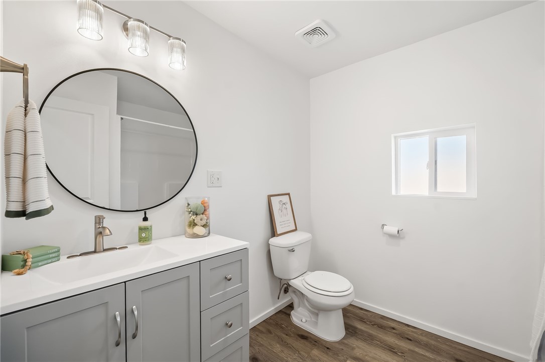 4392 Rio Verde Drive Fort Mohave, AZ 86426 - Photo 14 of 19 Bathroom featuring a white vanity with a single basin sink, gray cabinetry, and a round black-framed mirror