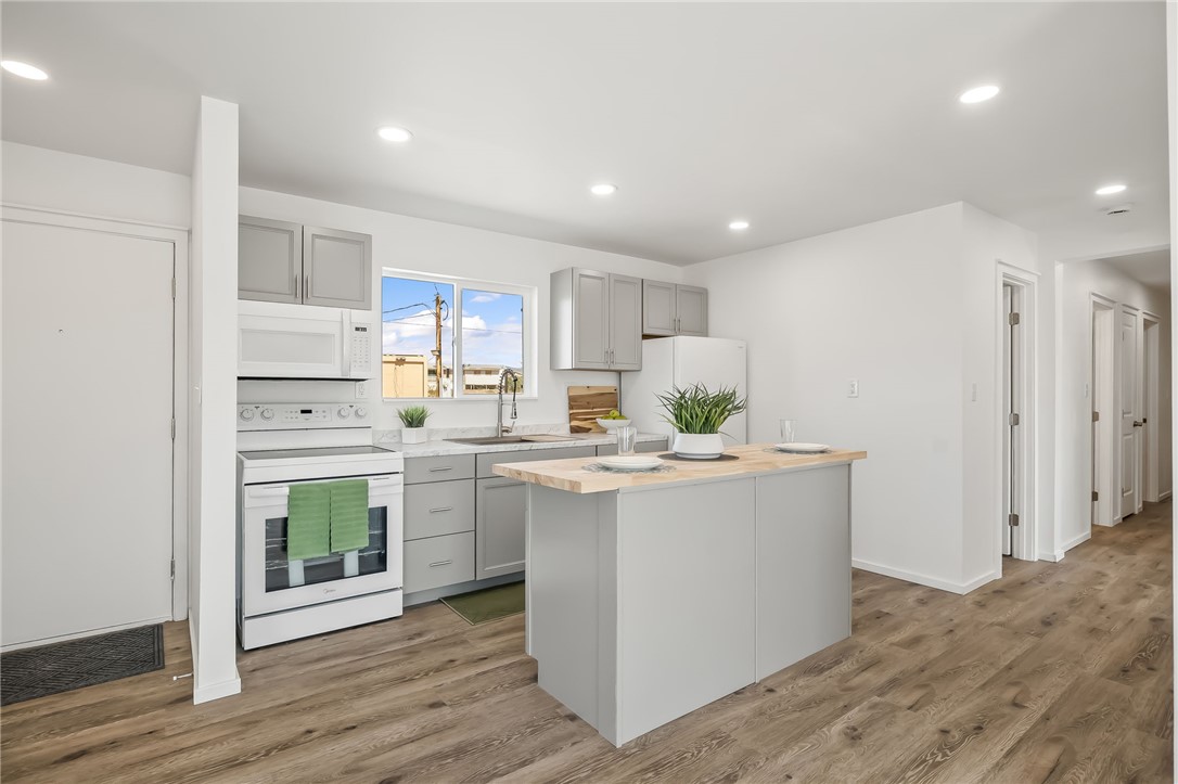 4392 Rio Verde Drive Fort Mohave, AZ 86426 - Photo 7 of 19 Kitchen featuring a central island with countertop seating, light gray cabinetry, white appliances, and wood-finish flooring