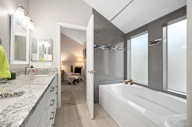 a bathroom with a granite countertop tub sink and mirror