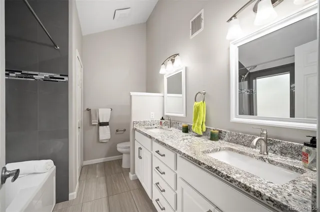 a bathroom with a granite countertop sink mirror vanity and toilet