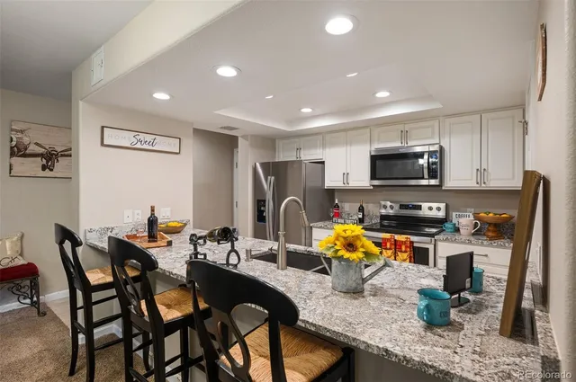 a kitchen with stainless steel appliances granite countertop a sink dishwasher a dining table and chairs with wooden floor