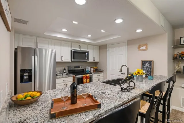a kitchen with stainless steel appliances granite countertop a sink a refrigerator and a wooden cabinets