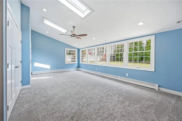 a view of an empty room with a window and a kitchen