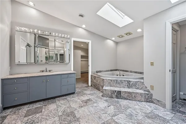 a spacious bathroom with a tub sink and mirror