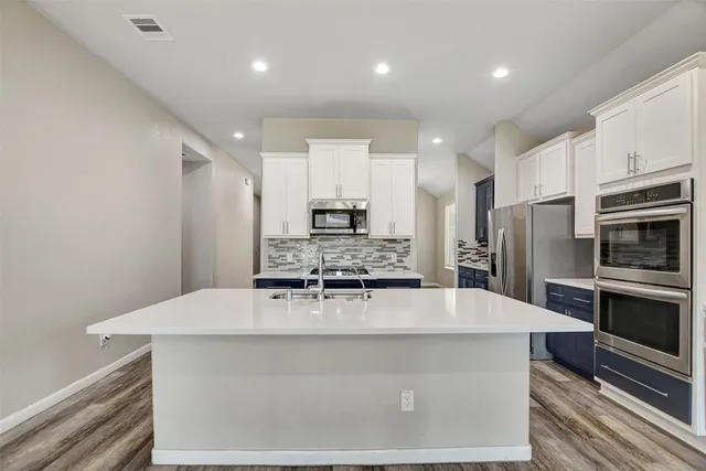 a large kitchen with stainless steel appliances a large counter top a stove and a refrigerator