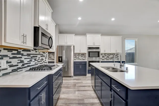 a kitchen with kitchen island granite countertop a stove a sink and a refrigerator with wooden cabinets