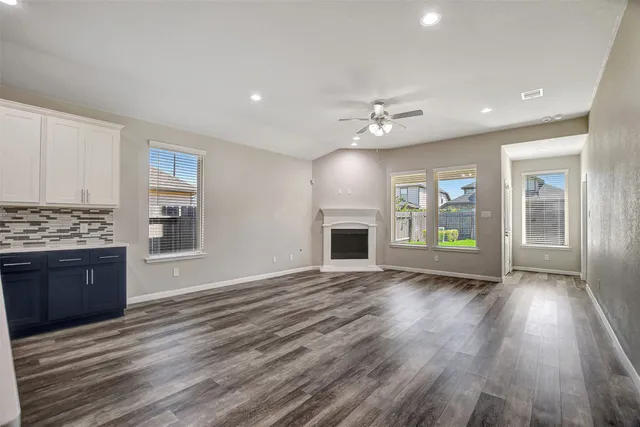 a view of an empty room with a kitchen and wooden floor