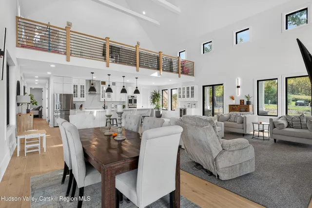 a kitchen with stainless steel appliances kitchen island granite countertop a refrigerator a stove a dining table and chairs with wooden floor