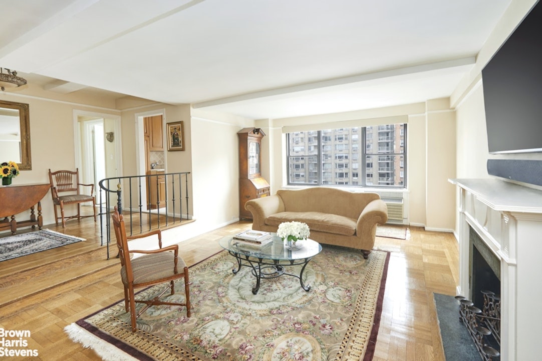 235 East 73rd Street, Unit 8D Manhattan, NY 10021 - Photo 1 of 10 a living room with furniture a fireplace and a floor to ceiling window