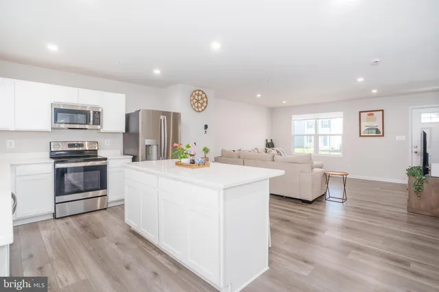 a kitchen with stainless steel appliances a refrigerator a stove a sink dishwasher and a refrigerator with wooden floor