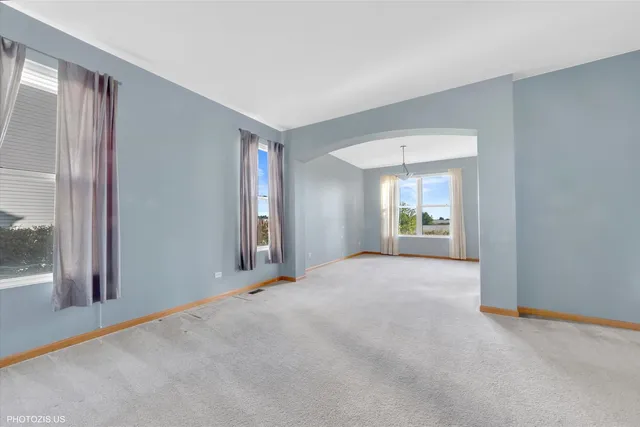 a view of an empty room with window and a kitchen
