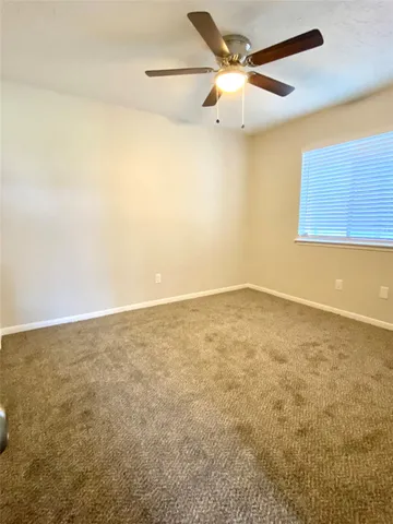 an empty room with a ceiling fan and a window