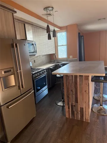 a kitchen with kitchen island a counter top space wooden floor and stainless steel appliances