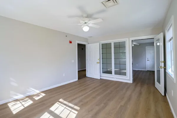 a view of an empty room with wooden floor and a window