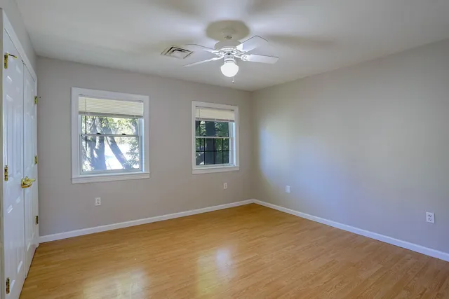 a view of an empty room with a window and wooden floor