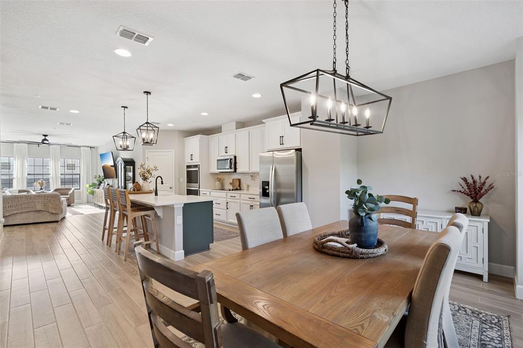 1230 Spotted Sandpiper Loop Winter Springs, FL 32708 - Photo 16 of 52 a dining room with wooden floor a chandelier a wooden table and chairs