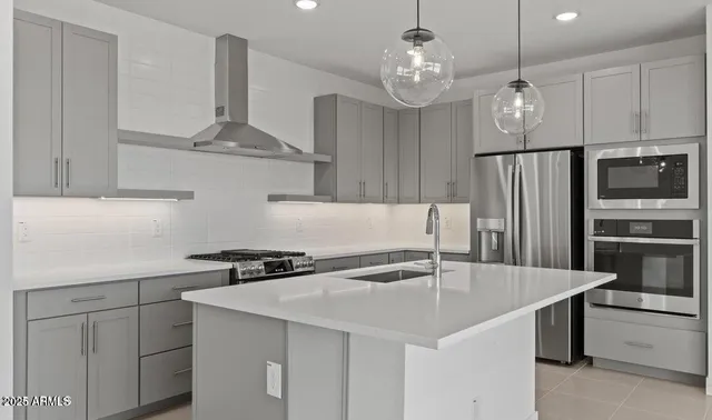 a kitchen with stainless steel appliances a sink a stove a refrigerator and cabinets