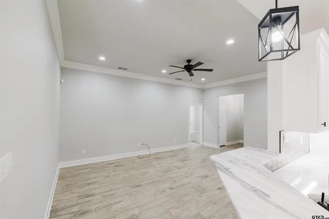 a view of a livingroom with a chandelier fan and wooden floor
