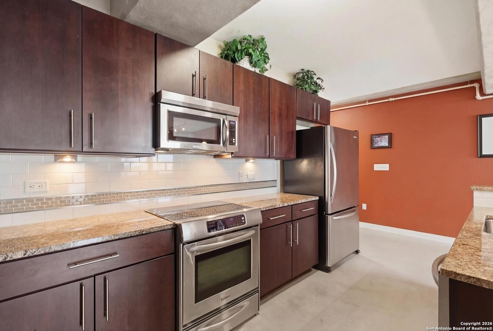 800 Brazos Street, Unit 1103 Austin, TX 78701 - Photo 11 of 26 a kitchen with granite countertop wooden cabinets stainless steel appliances and a counter space