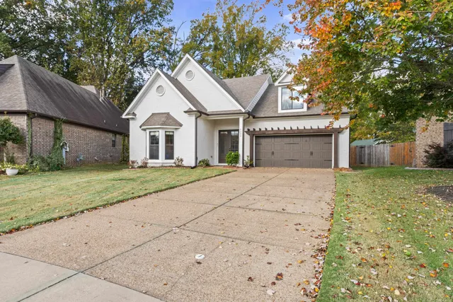 a front view of a house with a garden and trees