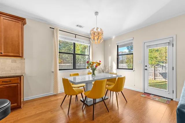 a dining room with furniture a chandelier and wooden floor
