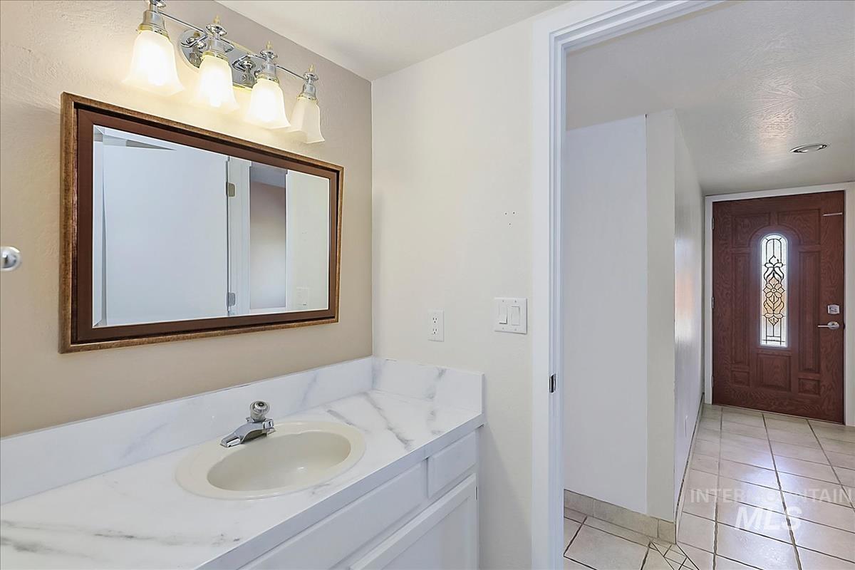 2804 West Sunrise Rim Road Boise, ID 83705 - Photo 12 of 50 Bathroom vanity featuring a white countertop with integrated sink, framed mirror, and chrome light fixture