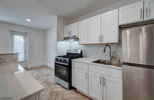 a kitchen with stainless steel appliances granite countertop a sink stove refrigerator and cabinets