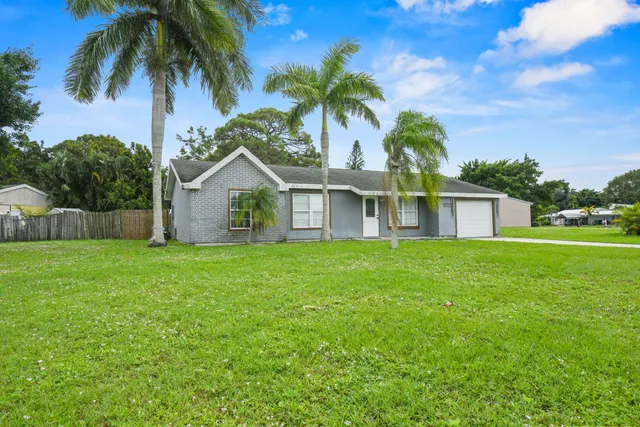 a view of a house with a yard and palm trees