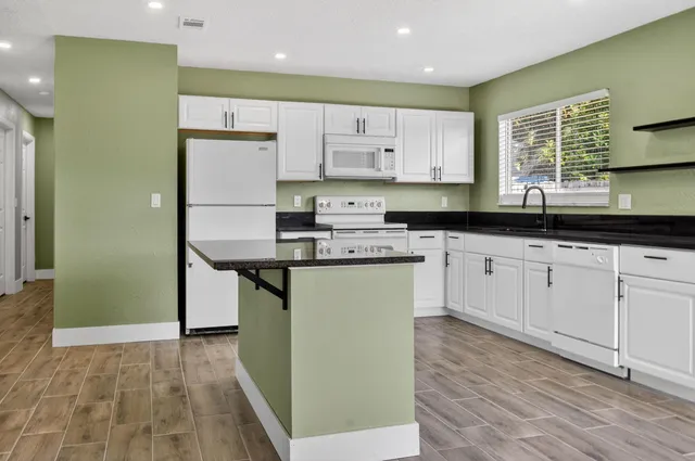 a kitchen with stainless steel appliances granite countertop a stove a sink and a refrigerator