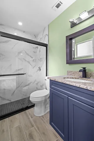 a bathroom with a granite countertop sink toilet and shower