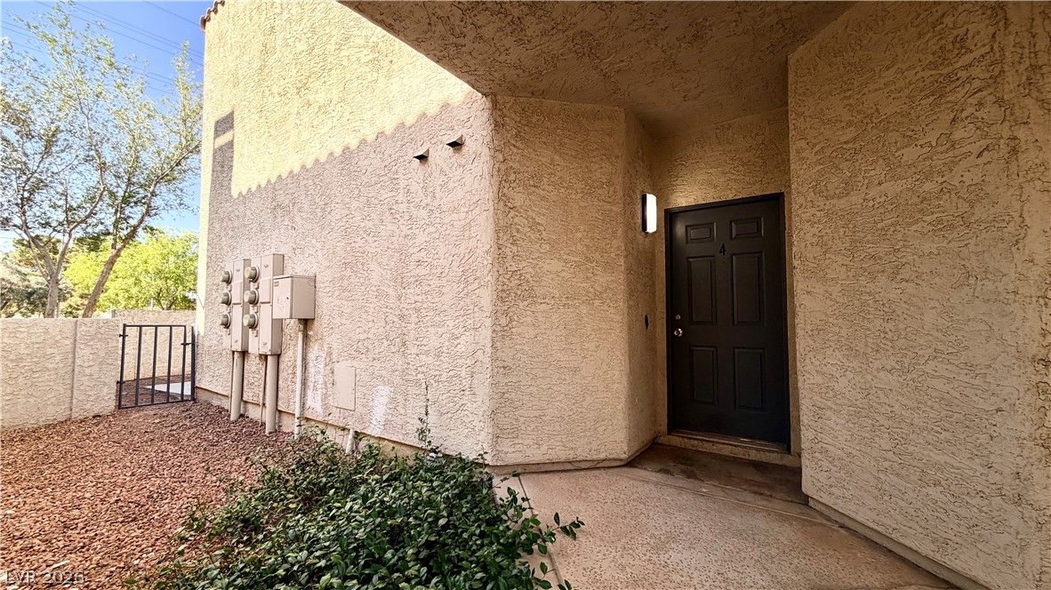 6250 West Flamingo Road, Unit 4 Las Vegas, NV 89103 - Photo 1 of 45 This entry features a private gate and a textured facade, leading to a dark paneled door.
