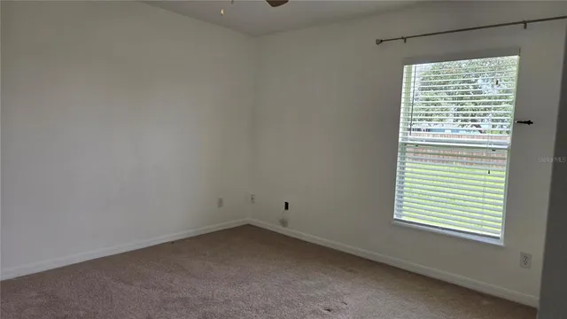 an empty room with a window and a ceiling fan