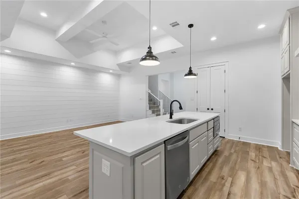 a large kitchen with kitchen island a stove a sink a refrigerator and white cabinets with wooden floor