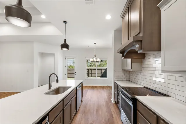 a kitchen with stainless steel appliances granite countertop a sink a stove and a wooden floor