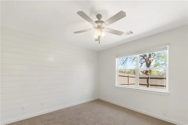 an empty room with window and ceiling fan