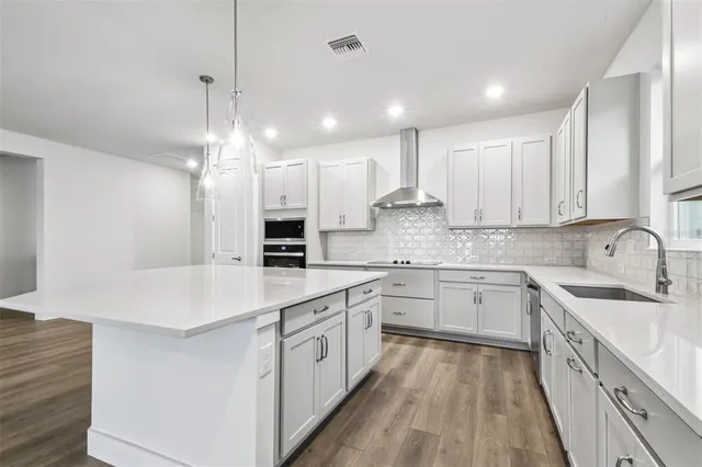 a kitchen that has a lot of cabinets and wooden floor