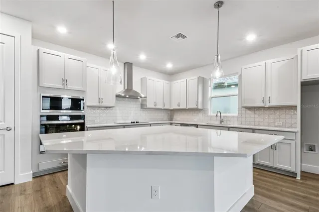 a view of kitchen with kitchen island wooden floors and stainless steel appliances