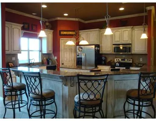 a kitchen with stainless steel appliances granite countertop a sink a stove and chairs