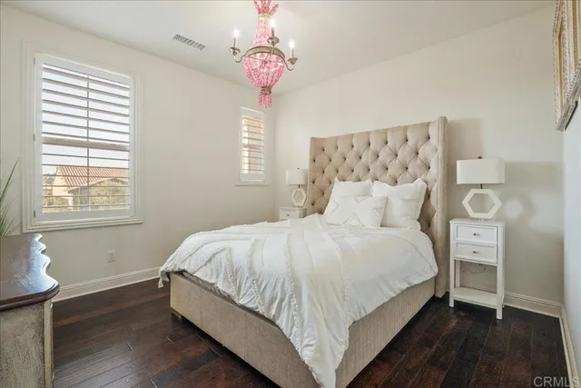 a large bed sitting in a bedroom next to a window and a chandelier