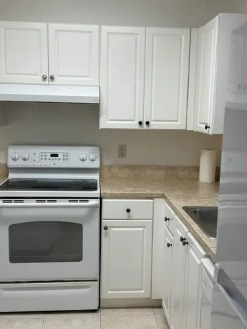 a kitchen with granite countertop white cabinets and white appliances