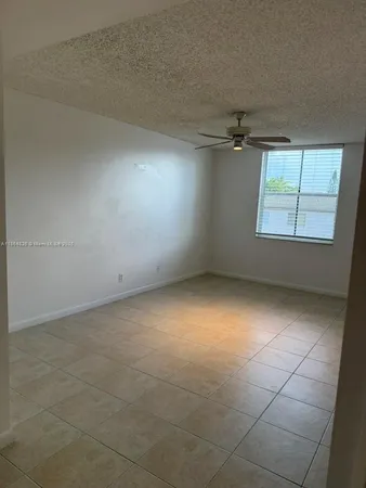 an empty room with windows and ceiling fan
