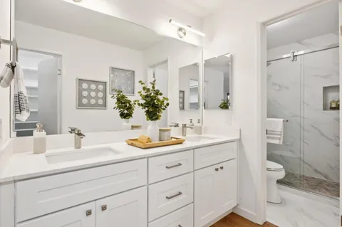 a bathroom with a double vanity sink toilet and shower