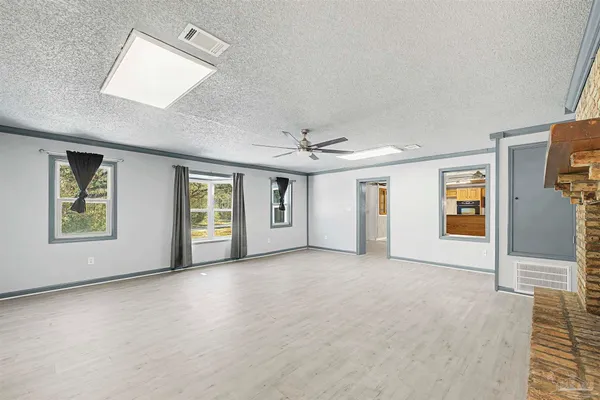 an empty room with windows and chandelier fan
